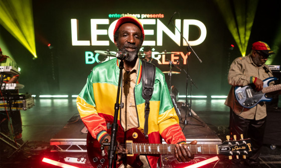 Bob Marley tribute playing guitar on stage
