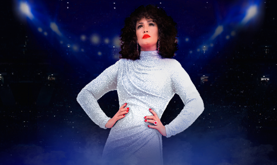 Belinda Davids as Whitney wearing a silver dress