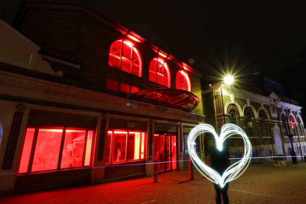 The Haymarket is completely lit up in red lights. A neon white heart is in the foreground.