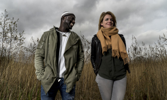 Catrin Finch & Seckou Keita stand in a wildflower field.