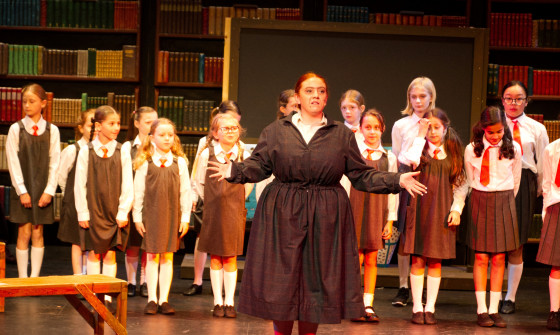 Cast of Matilda Jnr on stage. Mrs Trunchball at the front with the revolting children behind.