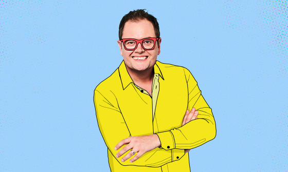 A cartoony looking Alan Carr in a bright yellow suit