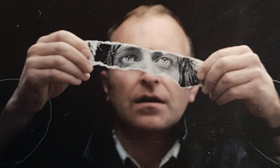 Simon Evans holding a piece of paper across his face with a pair of eyes on