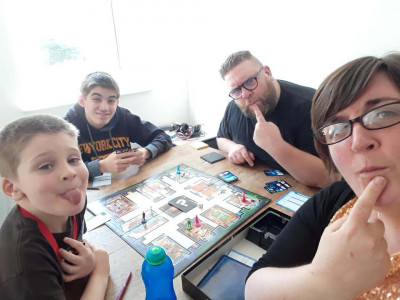 Duncan and family play a board game at a table, pulling silly faces.