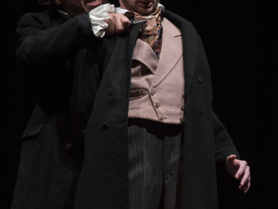 One man stands behind another with a knife to his neck