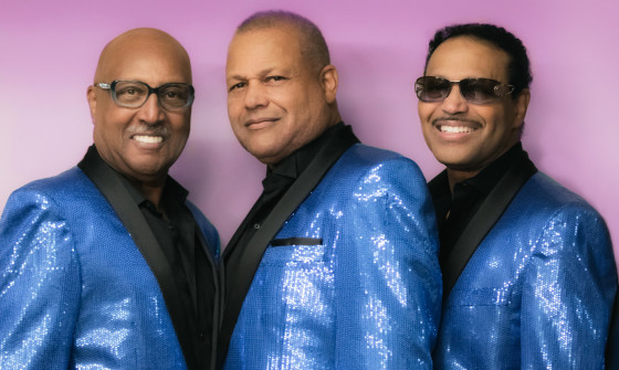 The Tavares wearing blue glitter suits, smiling at the camera