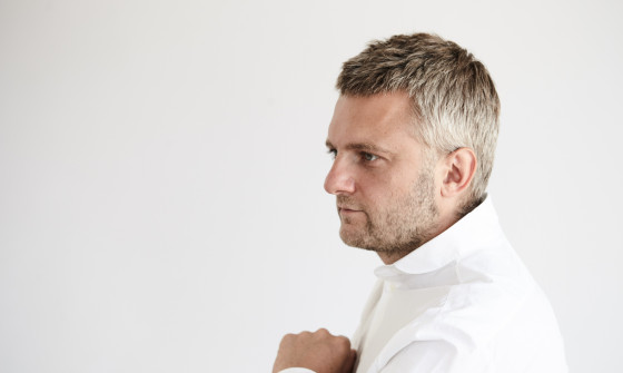 Kirill Karabits is standing sideways. He is wearing a white shirt