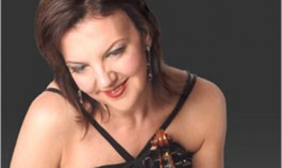 Tasmin Little is sat on the floor. Her violin is resting against her legs