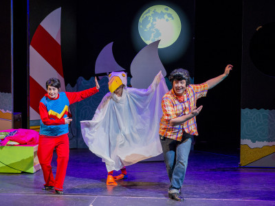 Three cast dance. The one in the middle is dressed as a bird.