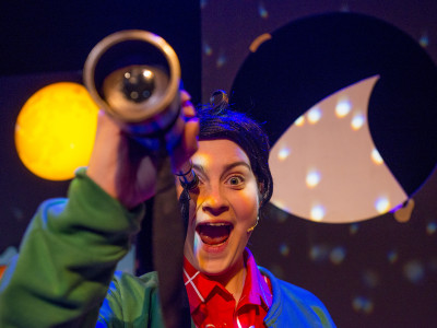 A child looks through a telescope and looks excited
