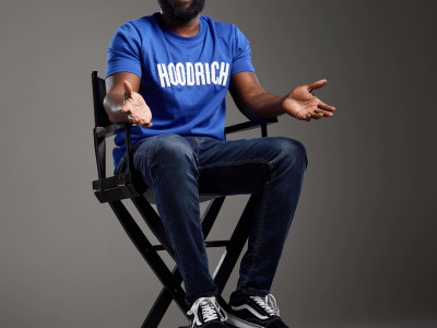 Kojo Anim sits in a director's chair, grinning