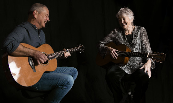 Peggy and Calum sit with guitars on their lap