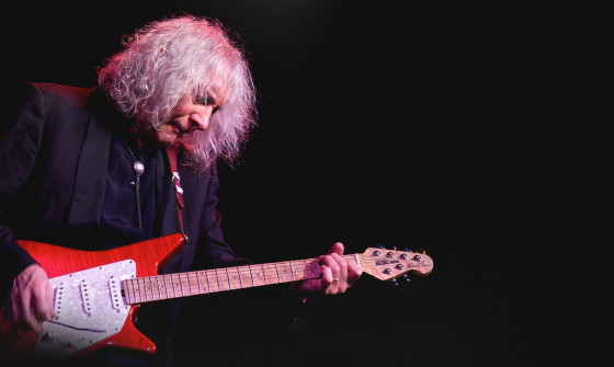 Albert Lee looks down at his guitar as he plays it