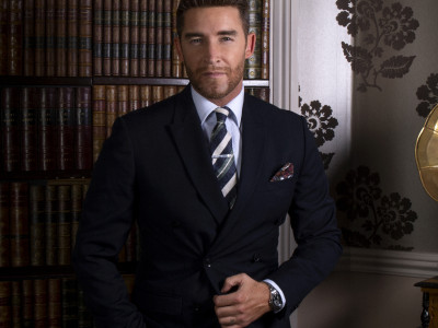The Overtones' Jay stands dressed in a suit looking into the camera