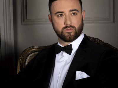 The Overtones' Mark sits in a chair looking beyond the camera. He is dressed in a suit