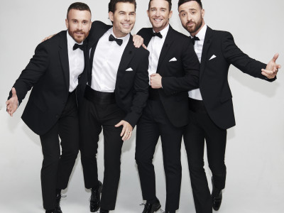 The Overtones stand dressed in suits smiling at the camera
