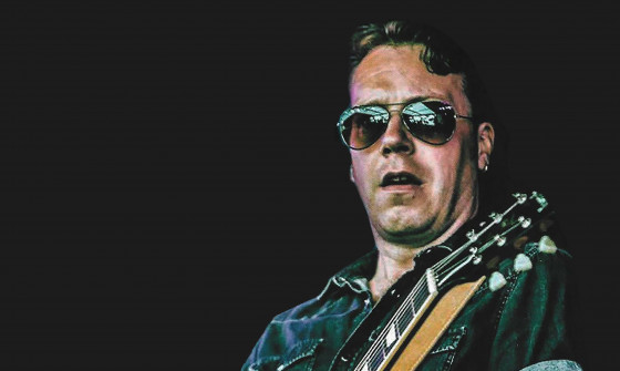 Jim Kirkpatric plays the guitar on stage in sunglasses