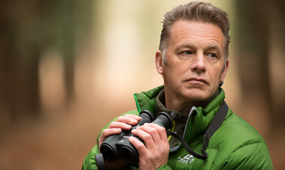 A photo of Chris Packham holding binoculars