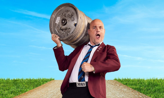 Al Murray carrying a beer barrel down a road